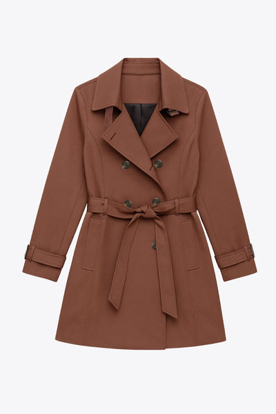 Abrigo trench corto de fit recto, con cuello solapa, bolsillos delanteros con vivos, detalle de bata trasera y manga larga. Trabillas, cinturón amarrable del mismo tejido y cierre frontal con doble cruce de botones en contraste. Detalle de trabilla y botón en hombros, bata trasera, cuello y puños.