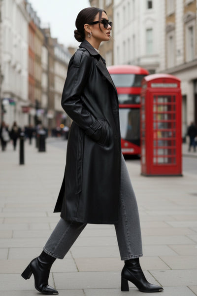 Abrigo trench de efecto piel, fit recto, con solapa, bolsillos delanteros con vivos, abertura posterior en bajo, bata trasera y manga larga. Cinturón amarrable del mismo tejido y cierre frontal con doble cruce de botones. Detalle de trabilla y botón en hombros y puños.