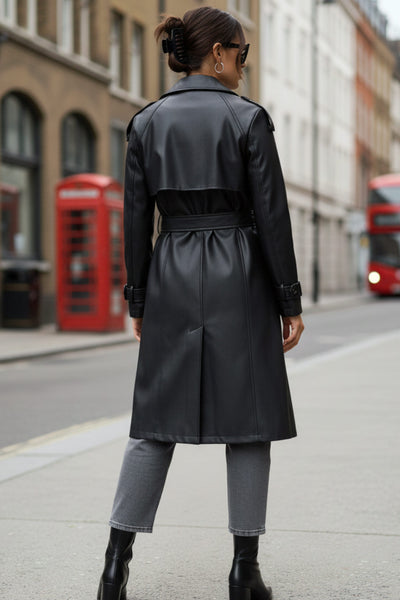 Abrigo trench de efecto piel, fit recto, con solapa, bolsillos delanteros con vivos, abertura posterior en bajo, bata trasera y manga larga. Cinturón amarrable del mismo tejido y cierre frontal con doble cruce de botones. Detalle de trabilla y botón en hombros y puños.