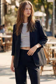 Blazer abierto de fit recto, manga 3/4 con doblez en puños, con solapa, hombreras y vivos frontales. Detalle de abertura posterior.