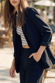 Blazer abierto de fit recto, manga 3/4 con doblez en puños, con solapa, hombreras y vivos frontales. Detalle de abertura posterior.