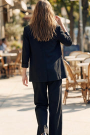 Blazer abierto de fit recto, manga 3/4 con doblez en puños, con solapa, hombreras y vivos frontales. Detalle de abertura posterior.