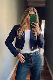 Blazer corto abierto, de fit recto, con solapa y hombreras, manga larga y detalle frontal de botones decorativos en contraste.