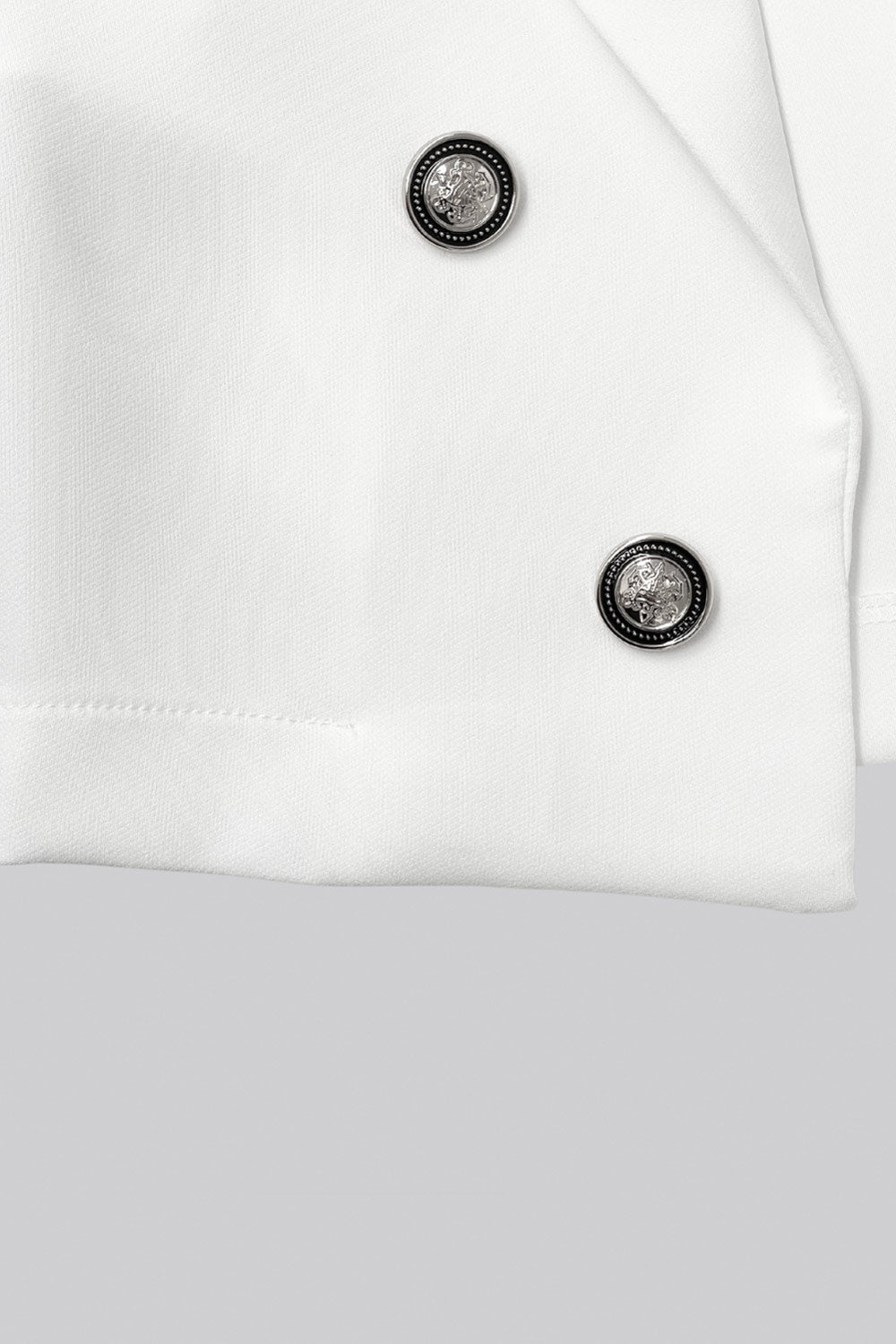 Blazer corto abierto, de fit recto, con solapa y hombreras, manga larga y detalle frontal de botones decorativos en contraste.