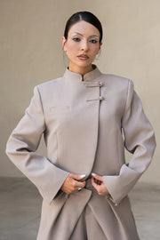 Blazer corto cruzado de manga larga con abertura en puños, cuello mao, vivo decorativo frontal, detalle de botones decorativos frontales y bajo curveado.