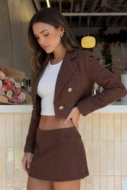 Blazer corto abierto de bouclé, fit recto, con solapa, manga larga y botones decorativos en contraste.