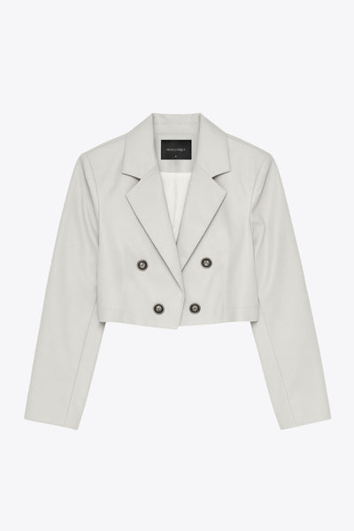 Blazer corto abierto de efecto piel, fit recto, con hombreras y solapa, manga larga y botones decorativos frontales en contraste.