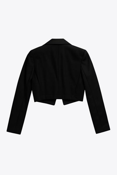 Blazer corto abierto de efecto piel, fit recto, con hombreras y solapa, manga larga y botones decorativos frontales en contraste.