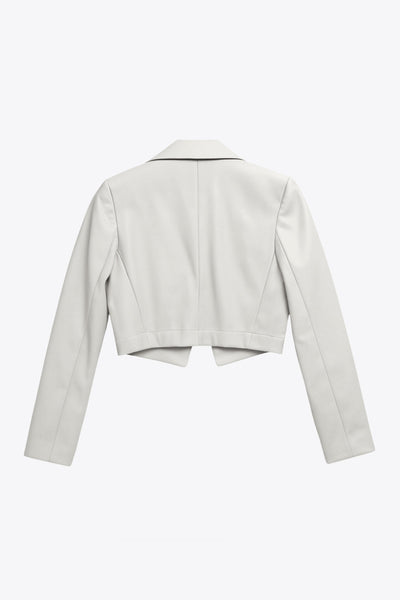 Blazer corto abierto de efecto piel, fit recto, con hombreras y solapa, manga larga y botones decorativos frontales en contraste.