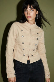 Blazer corto de fit ajustado, cuello mao, manga larga, trabillas decorativas con botones en puños y hombros, detalle frontal con botones decorativos en contraste y cierre frontal con hilera de broches ocultos.