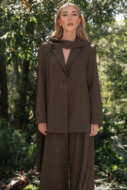 Blazer de fit oversized, con solapa y hombreras, manga larga, bolsillos delanteros con vivos y cierre frontal con botón. Detalle decorativo en cuello.