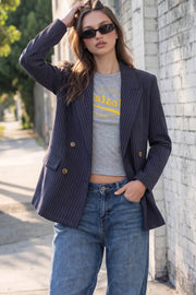 Blazer cruzado de fit oversized, estampado rayas, con solapa y hombreras, manga larga, bolsillos delanteros con cartera. Cierre frontal con doble botón en contraste.