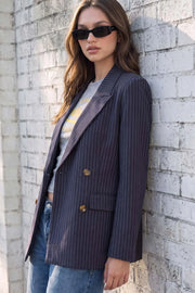 Blazer cruzado de fit oversized, estampado rayas, con solapa y hombreras, manga larga, bolsillos delanteros con cartera. Cierre frontal con doble botón en contraste.