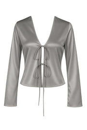 Blusa satinada abierta de fit fluido, escote v, manga larga amplia con abertura en puños y cierre frontal con lazo amarrable.