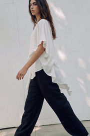 Blusa asimétrica de fit fluido, manga seguida con olanes, plisados y capas de olanes decorativos. Detalle de bajo asimétrico y textura en tejido.