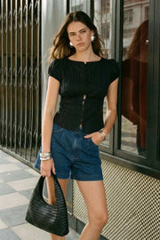 Blusa corta de rayas, fit ajustado, manga corta abullonada con rib elástico en borde, cuello redondo y cierre frontal con botones. Detalle de cortes y plisados decorativos frontales.