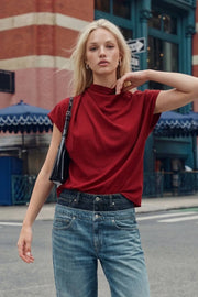 Blusa de cuello alto fluido, plisados en hombros, manga corta seguida y fit recto. Cierre posterior con botón y ojal.