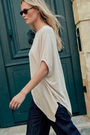 Blusa de fit fluido, cuello barco, manga corta seguida y bajo asimétrico diagonal.