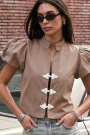 Blusa corta de fit recto, manga corta abullonada con plisados en hombros, cuello mao y escote v. Cierre frontal con botones alamares.