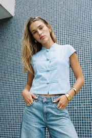 Blusa corta de fit recto, cuello mao, manga corta y cierre frontal con botones alamares.