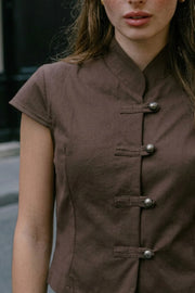 Blusa corta de fit recto, cuello mao, manga corta y cierre frontal con botones alamares.