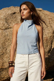 Blusa de estampado rayas, cuello halter fluido, escote en espalda con lazo amarrable posterior, cierre con botón y ojal.