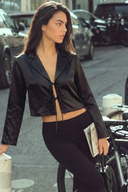 Blusa corta satinada de fit fluido, manga larga, escote v con solapa y cierre frontal con lazos amarrables.