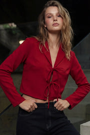 Blusa corta de fit fluido, manga larga, escote v con solapa y cierre frontal con lazos amarrables.