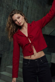 Blusa corta de fit fluido, manga larga, escote v con solapa y cierre frontal con lazos amarrables.