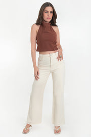 Blusa corta de cuello halter con escote fluido, sin mangas y escote en espalda con tirantes delgados ajustables. Cierre posterior con botón y ojal.