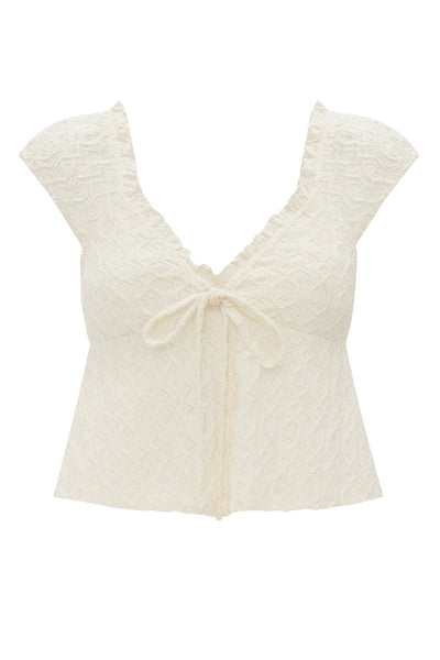 Blusa corta de escote v con cortes, olanes en borde y lazo decorativo frontal, manga corta y peplum con olanes en bajo. Detalle de textura en tejido.