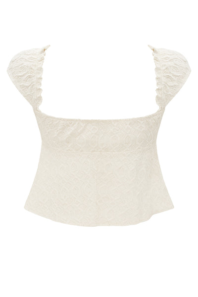 Blusa corta de escote v con cortes, olanes en borde y lazo decorativo frontal, manga corta y peplum con olanes en bajo. Detalle de textura en tejido.