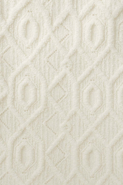 Blusa corta de escote v con cortes, olanes en borde y lazo decorativo frontal, manga corta y peplum con olanes en bajo. Detalle de textura en tejido.