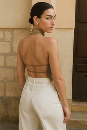 Blusa corta satinada de cuello halter con escote fluido, sin mangas y escote en espalda con tirantes delgados ajustables.