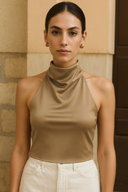 Blusa corta satinada de cuello halter con escote fluido, sin mangas y escote en espalda con tirantes delgados ajustables.