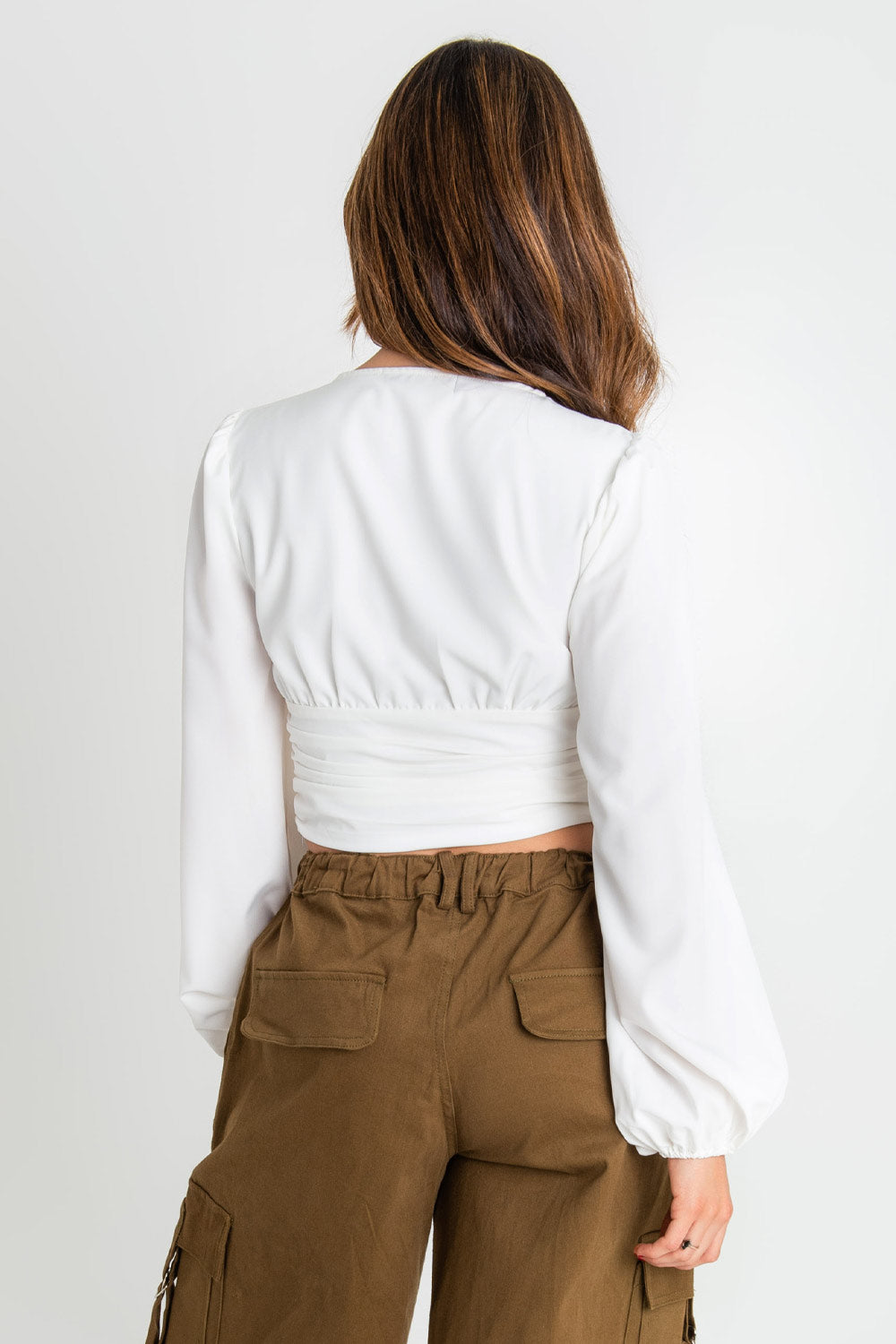 Blusa corta de manga larga abullonada, escote v con detalles plisados, cortes frontales y plisados en costados.