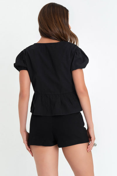 Blusa de manga corta abullonada con rib elástico en bordes, escote v y cierre frontal con lazos amarrables. Detalle de peplum con olanes en bajo.