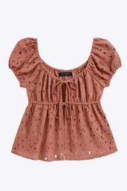 Blusa corta eyelet de manga corta abullonada, rib elástico en cintura, escote redondo con plisados y cierre frontal con lazos amarrables. Detalle de perforado en tejido bordado.