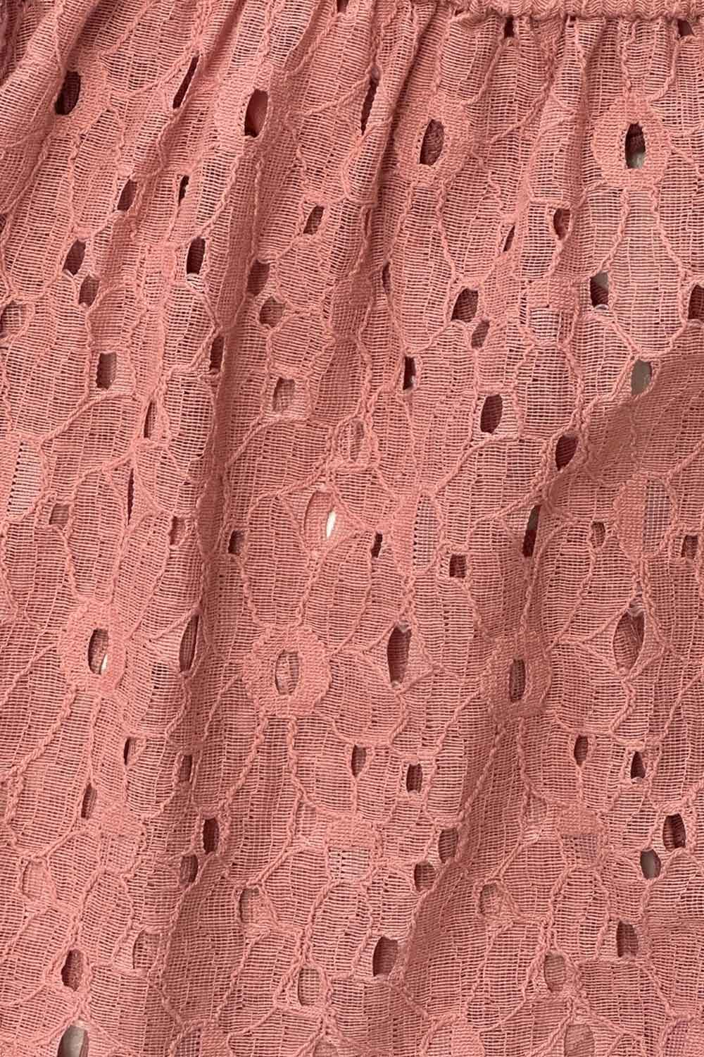 Blusa corta eyelet de manga corta abullonada, rib elástico en cintura, escote redondo con plisados y cierre frontal con lazos amarrables. Detalle de perforado en tejido bordado.