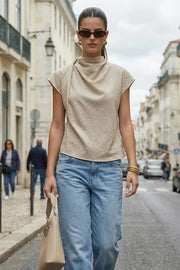 Blusa fluida de manga corta seguida, cuello mock seguido con plisados decorativos en hombro y cuello. Cierre posterior con botones y ojales.