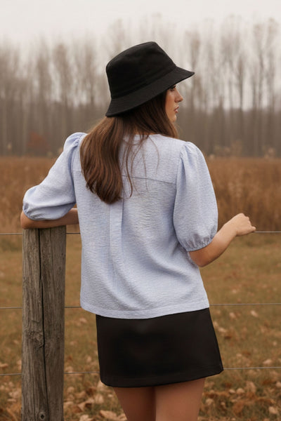 Blusa de fit fluido, estampado rayas, manga corta abullonada con rib elástico en bordes, cuello redondo y escote v. Cierre frontal con doble lazo amarrable en contraste y pinza amplitud en espalda.