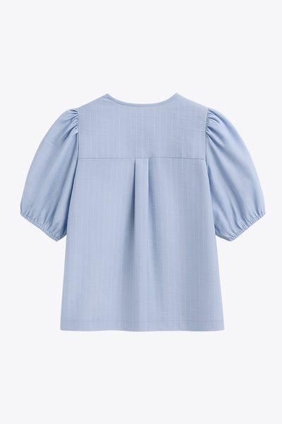 Blusa de fit fluido, estampado rayas, manga corta abullonada con rib elástico en bordes, cuello redondo y escote v. Cierre frontal con doble lazo amarrable en contraste y pinza amplitud en espalda.