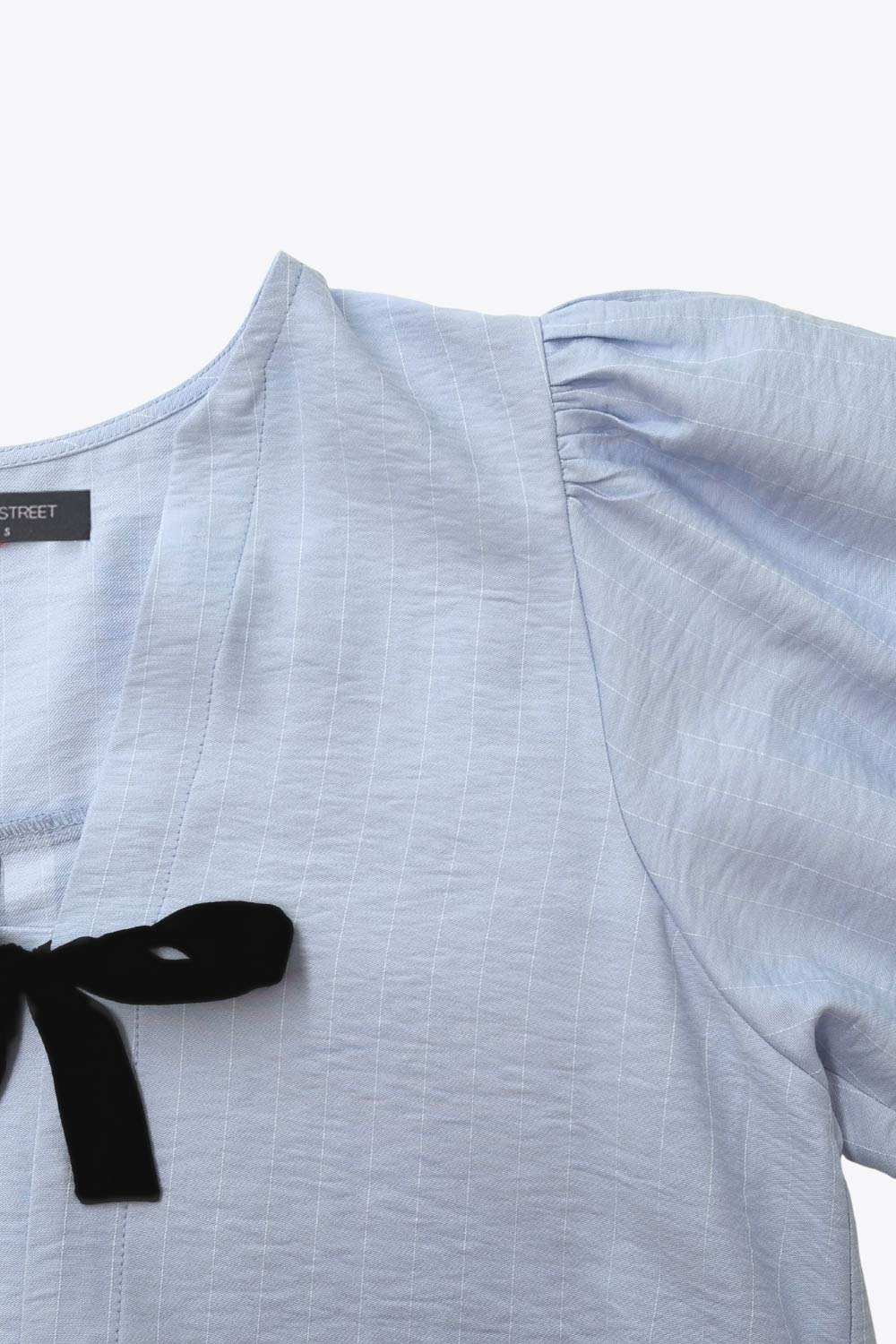 Blusa de fit fluido, estampado rayas, manga corta abullonada con rib elástico en bordes, cuello redondo y escote v. Cierre frontal con doble lazo amarrable en contraste y pinza amplitud en espalda.