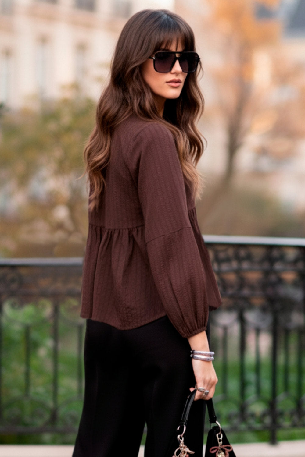 Blusa de fit fluido, manga larga abullonada con rib elástico en puños, escote v, plisados decorativos en hombros y peplum con olanes en bajo. Cierre frontal con hilera de botones.