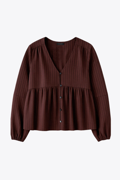 Blusa de fit fluido, manga larga abullonada con rib elástico en puños, escote v, plisados decorativos en hombros y peplum con olanes en bajo. Cierre frontal con hilera de botones.