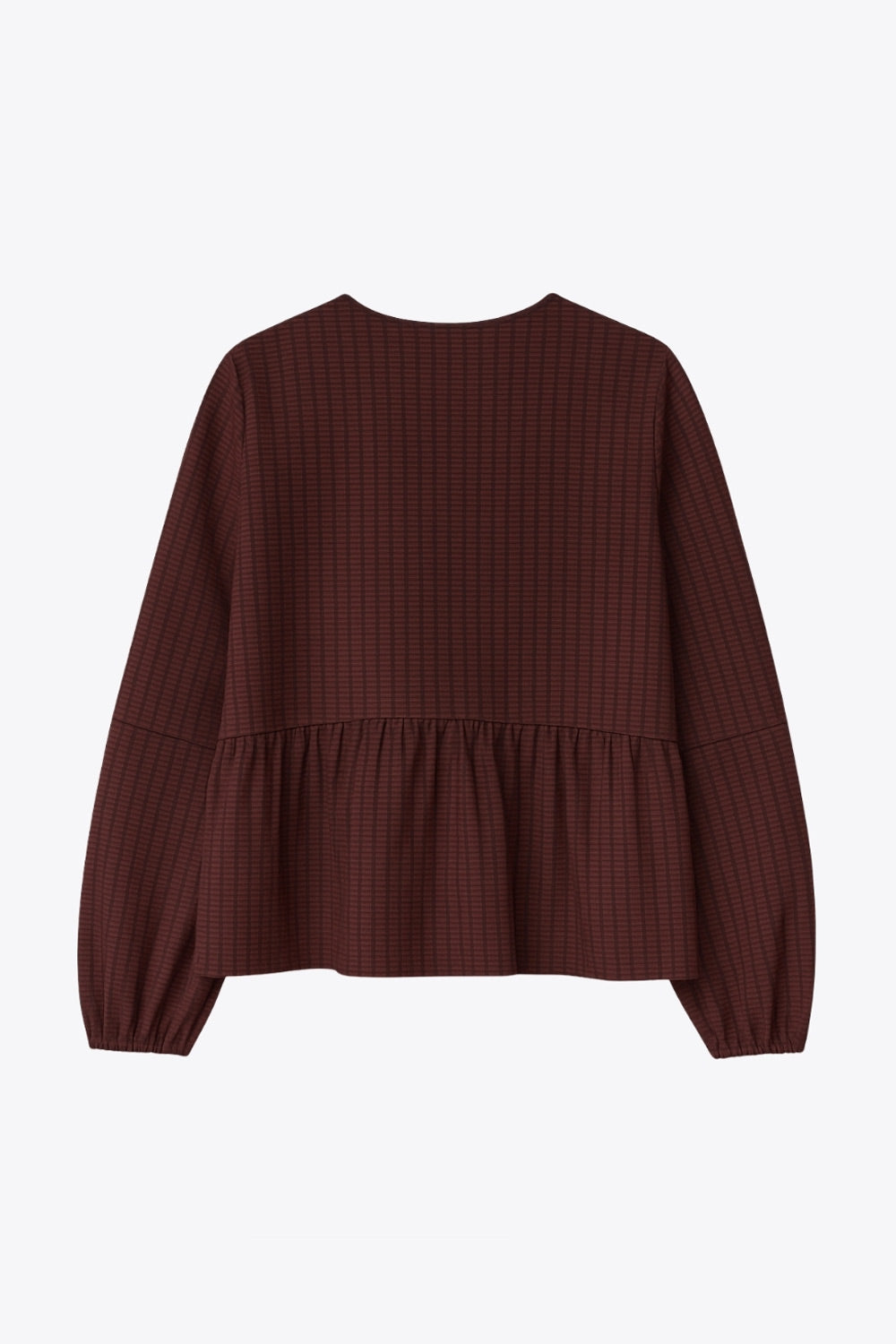 Blusa de fit fluido, manga larga abullonada con rib elástico en puños, escote v, plisados decorativos en hombros y peplum con olanes en bajo. Cierre frontal con hilera de botones.