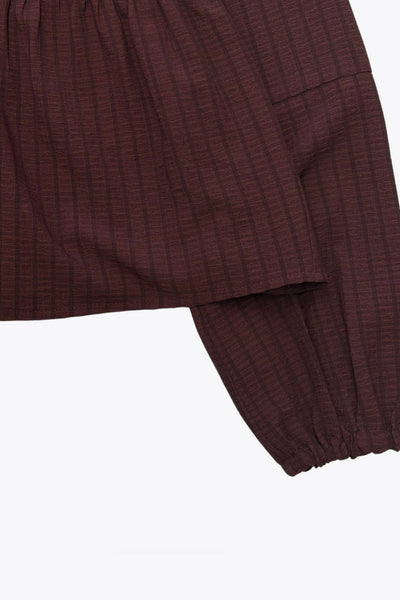 Blusa de fit fluido, manga larga abullonada con rib elástico en puños, escote v, plisados decorativos en hombros y peplum con olanes en bajo. Cierre frontal con hilera de botones.