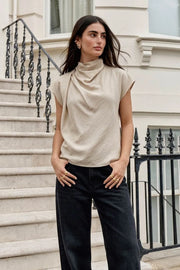 Blusa fluida de manga corta seguida, cuello mock seguido con plisados decorativos en hombro y cuello. Cierre posterior con botones y ojales.