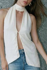Blusa fluida de cuello alto halter, sin mangas, bajo asimétrico, escote frontal y en espalda.