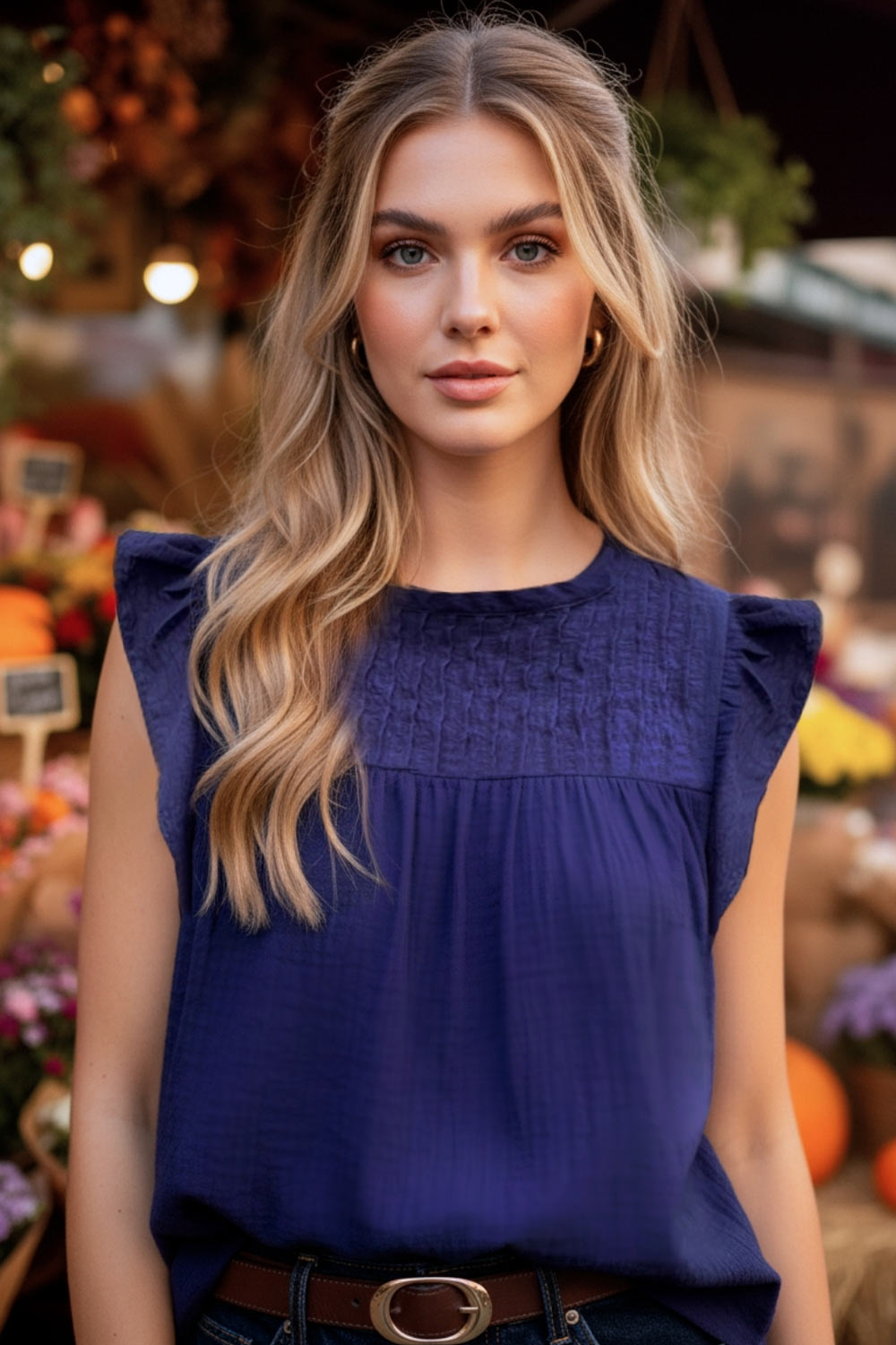 Blusa de fit recto, cuello redondo, sin mangas, olanes en sisa y costuras decorativas frontales con plisados. Cierre posterior con botón y ojal.